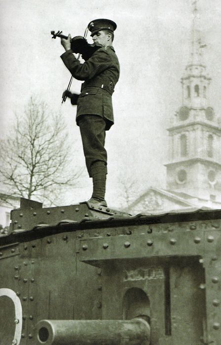 British officier playng violin on the top of a tank. WW1. Gun below him is a 6 pounder 57mm Church behind him says London,so maybe a memorial service in London after the Great War.